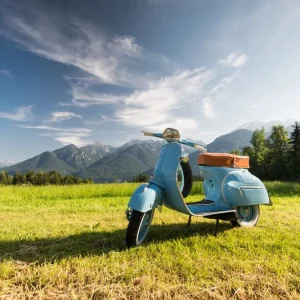 Blaue Vespa vor Bergkulisse auf Feld Acheter En Ligne